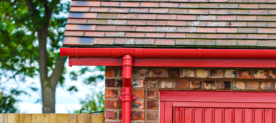 Aluminium red half round guttering with traditional cast round downpipes | Garston Barns Aluminium red half round guttering with traditional cast round downpipes fitted to outbuilding at Garston Barns